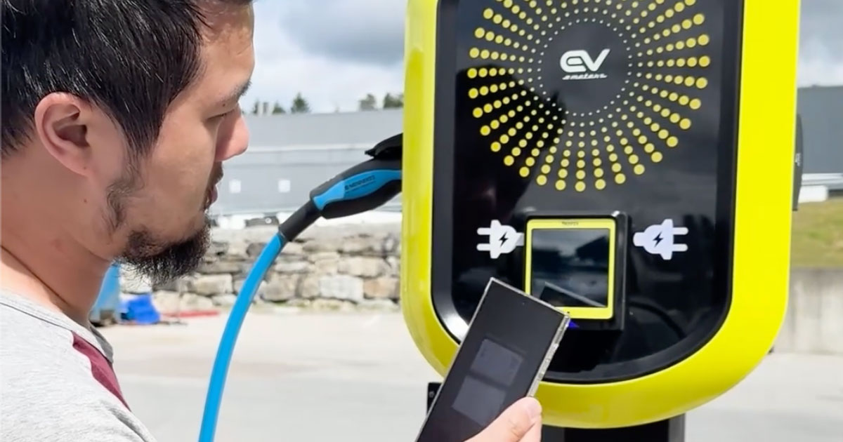 Mann betaler med mobil på ladestasjonen EV Meter Pay2